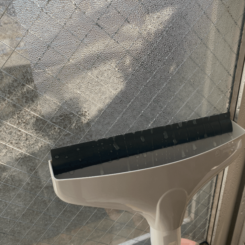 山﨑産業の結露とりワイパーで窓の結露をとっている様子